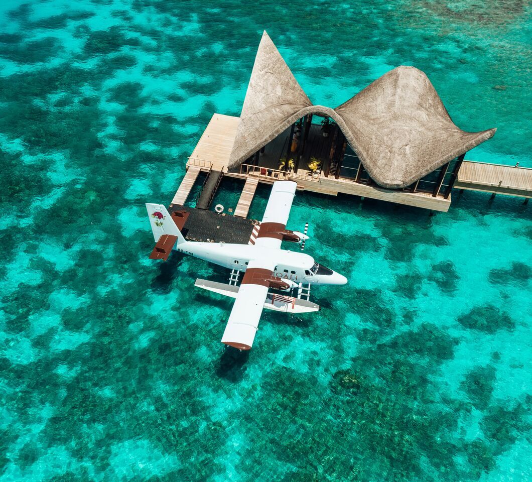 Seaplane moored at the overwater arrival jetty of JOALI Maldives, surrounded by turquoise lagoon
